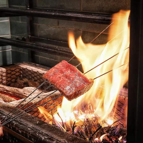 焼き網の上で炎に炙られる薄切り和牛