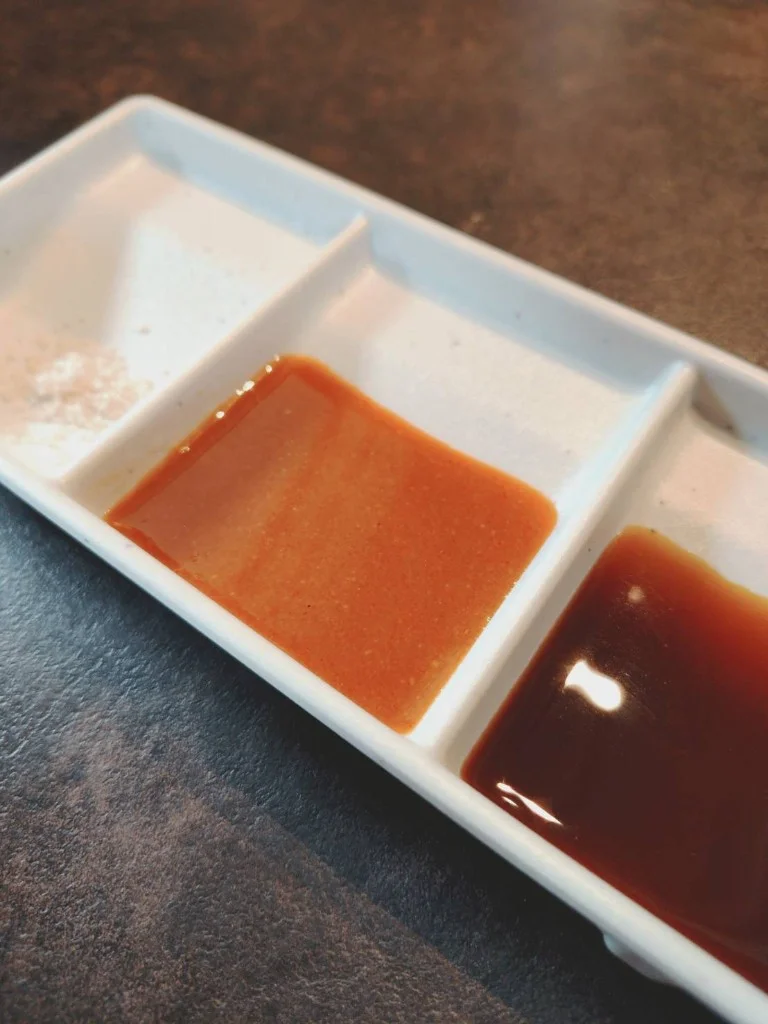木のテーブルに並ぶ焼肉用のたれと薬味の小皿